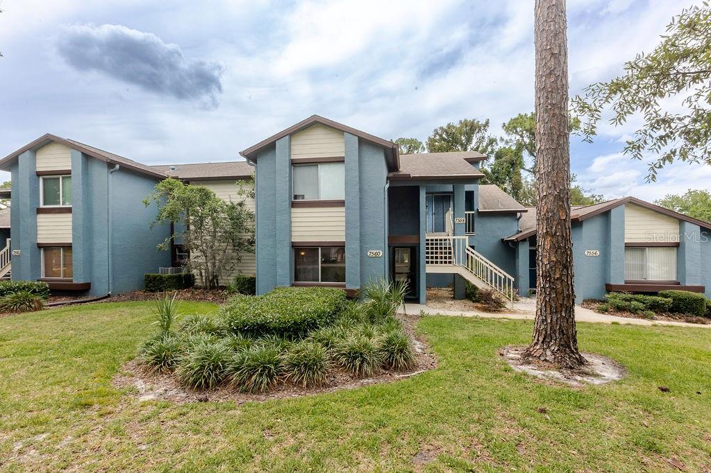 A multi-unit residential building with blue stucco siding and tan accents sits on a lawn — 7560 ST ANDREWS BOULEVARD UNIT 7560, WEEKI WACHEE, FL