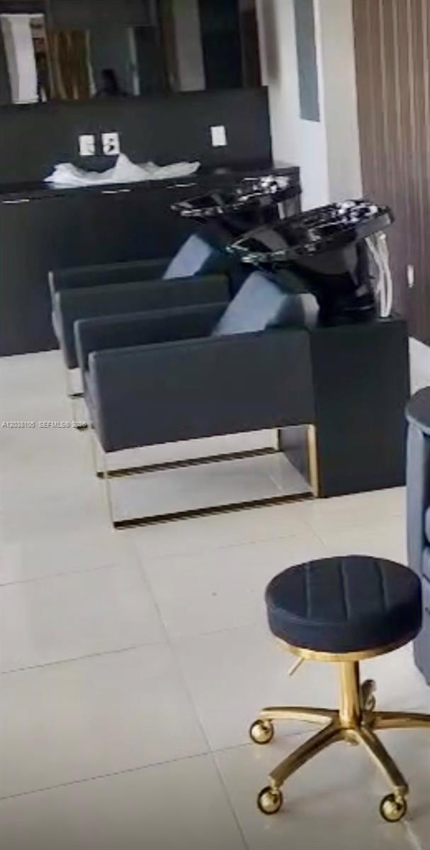 A salon area features two black shampoo stations and a rolling stool with gold accents — CORAL GABLES, FL