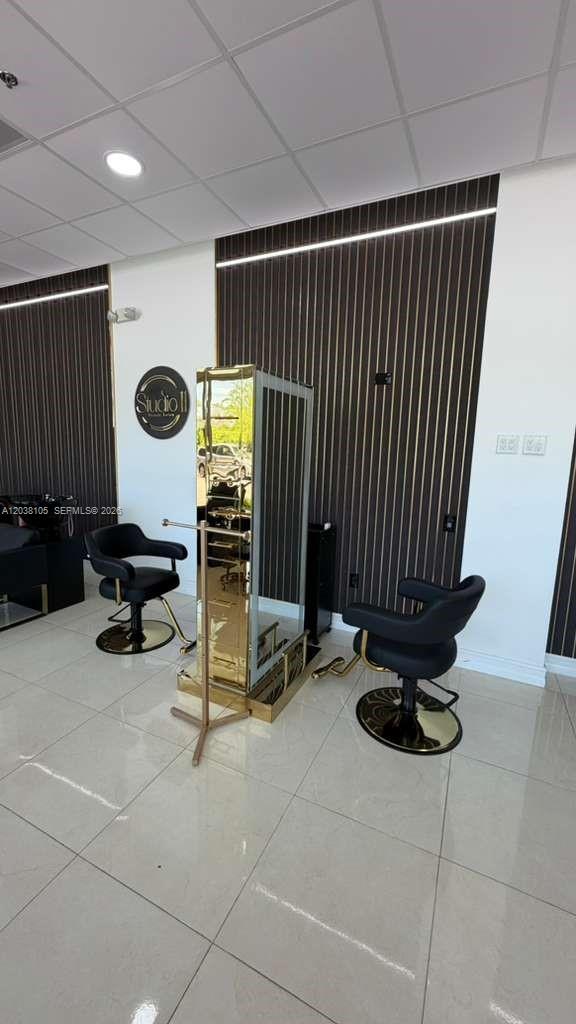A modern salon space features two black chairs facing a central gold-mirrored styling station — CORAL GABLES, FL