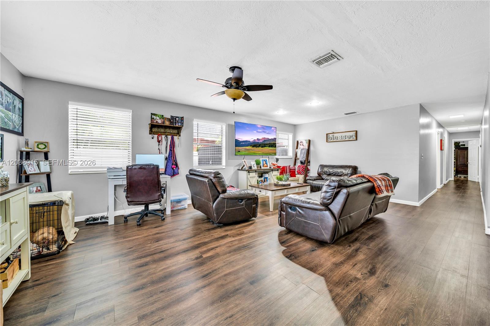 A living room features dark wood-look flooring, leather furniture, a ceiling fan, and a television — 875 E 29th St # 1, Hialeah FL 33013, HIALEAH, FL