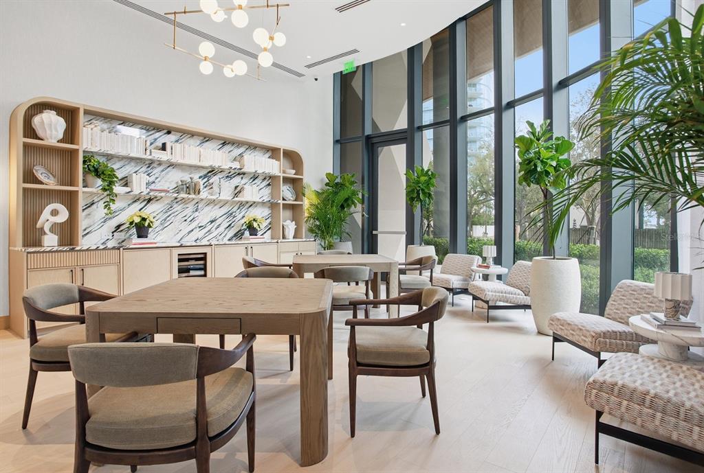 A modern lobby features a geometric rug, neutral sofas, orange armchairs, and a large chandelier — 3015 S YSABELLA AVENUE UNIT 603, TAMPA, FL