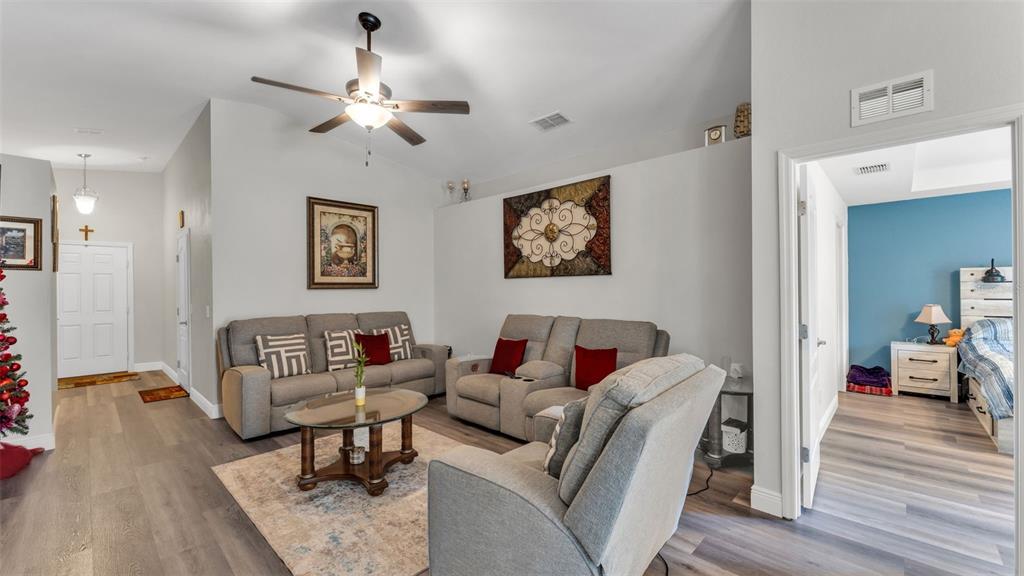 A living room features gray furniture, a ceiling fan, and wood-look flooring — 302 BROOKSHIRE DRIVE, LAKE WALES, FL