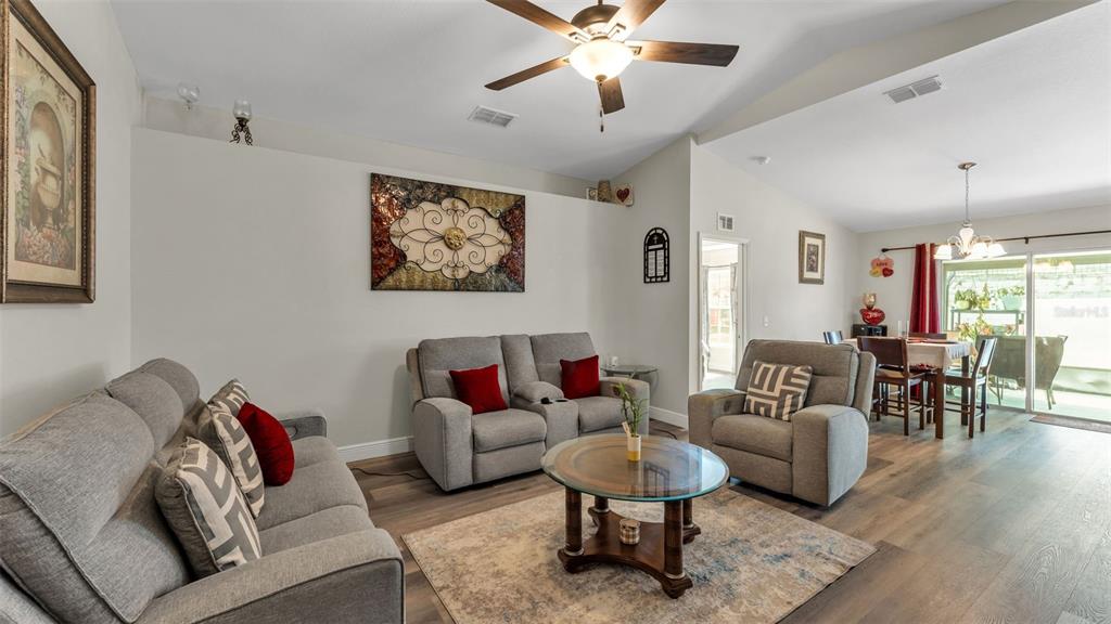 A living room with gray furniture, a glass coffee table, and an adjacent dining area — 302 BROOKSHIRE DRIVE, LAKE WALES, FL