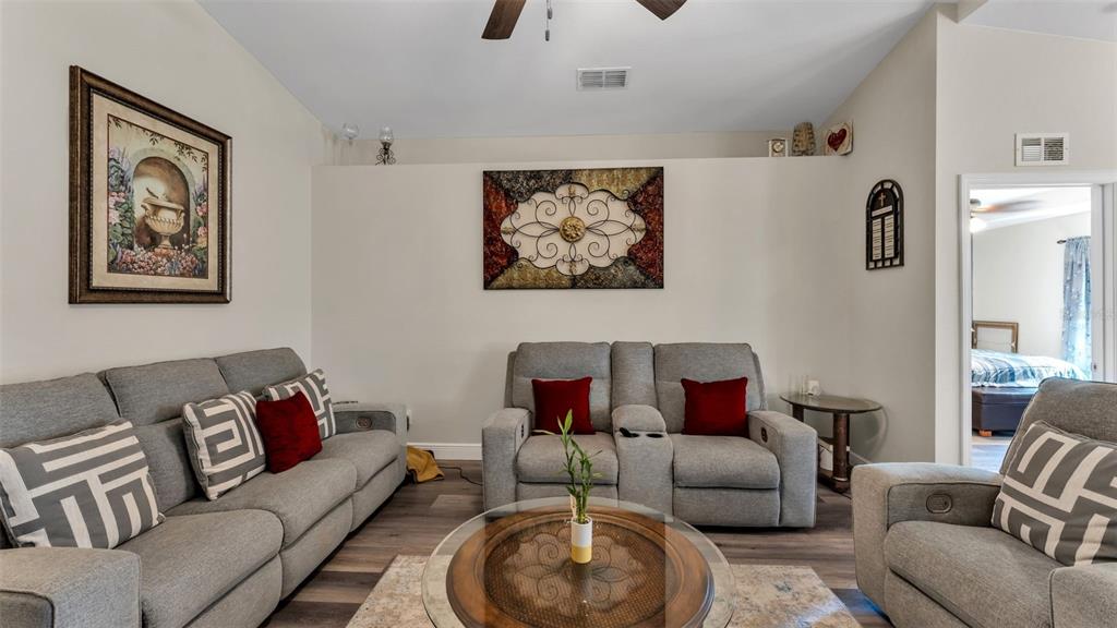 A living room features gray sofas, a glass coffee table, and wall art — 302 BROOKSHIRE DRIVE, LAKE WALES, FL