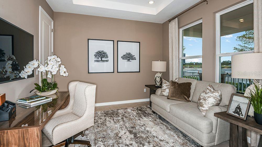 A home office features a desk, an upholstered chair, a sofa, and two framed tree prints — 617 MOON SHELL CIRCLE, NEW SMYRNA BEACH, FL