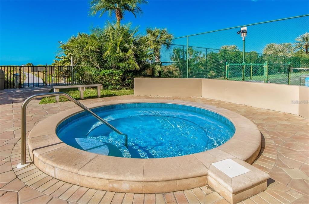A round outdoor hot tub with a metal handrail sits on a paved patio area — 1230 GULF BOULEVARD UNIT 1402, CLEARWATER BEACH, FL