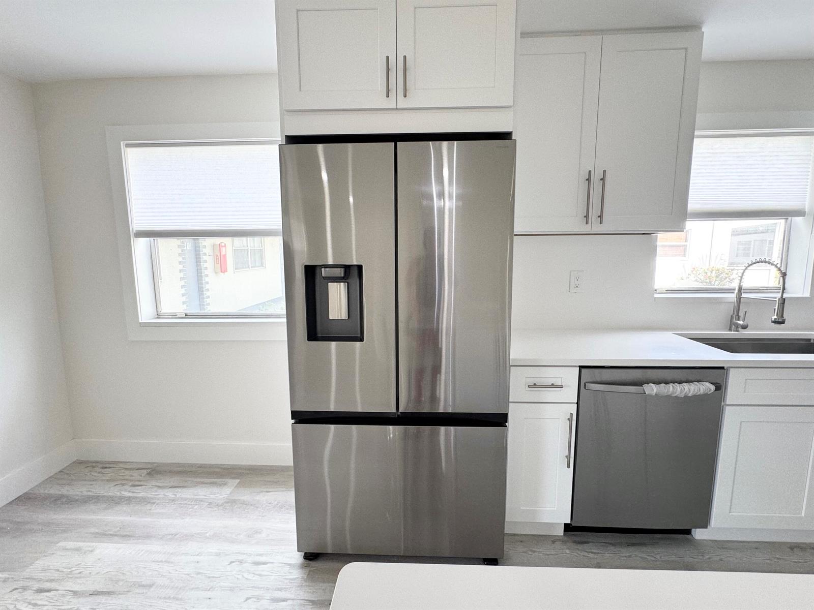 A kitchen features white cabinets, stainless steel appliances, and light-colored wood-look flooring — 108 Brittany # C, Delray Beach FL 33446, DELRAY BEACH, FL