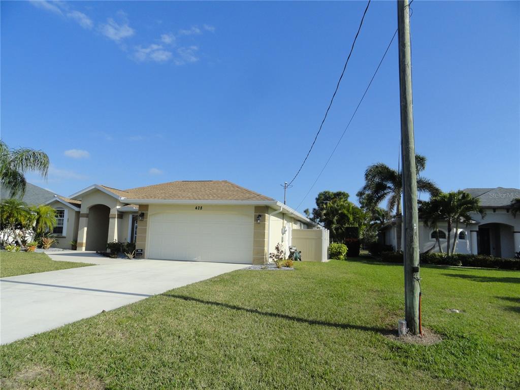 A single-story house with a beige exterior, a two-car garage, and a concrete driveway — 428 BOUNDARY BOULEVARD, ROTONDA WEST, FL