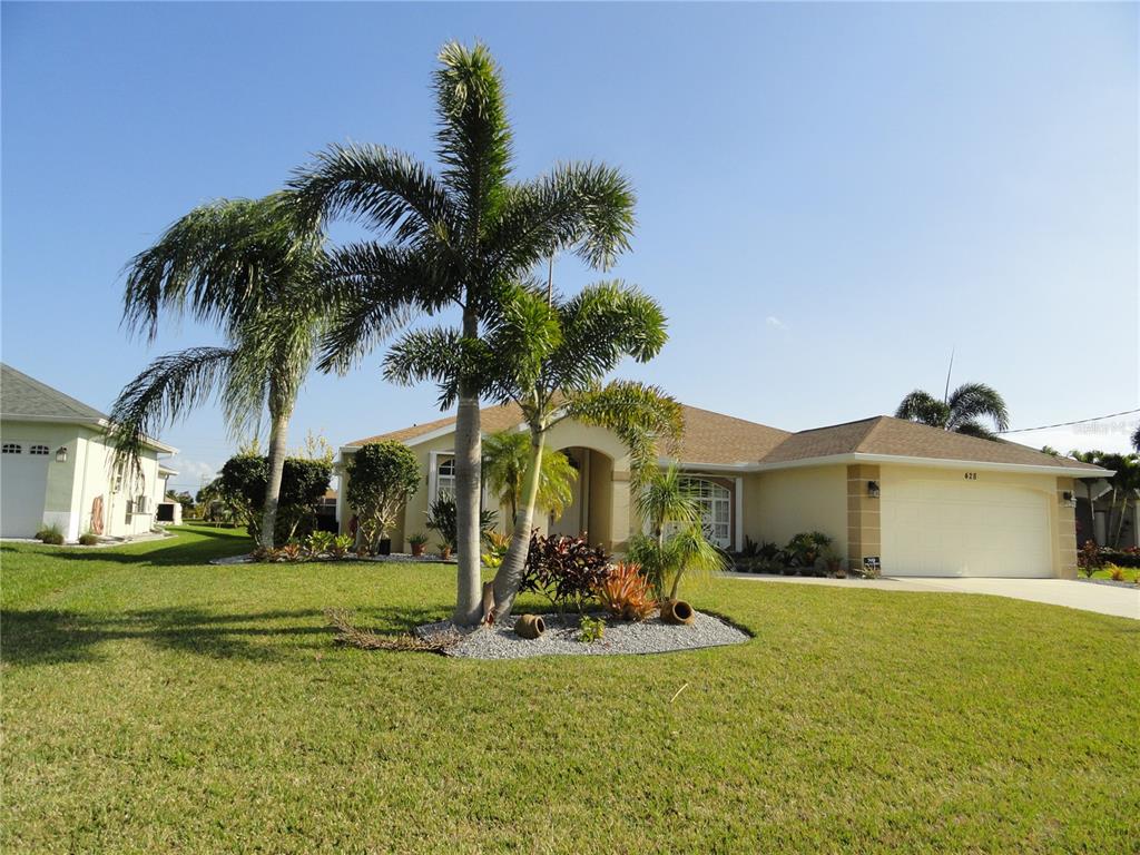 A single-story house with a tan exterior, a two-car garage, and palm trees in front — 428 BOUNDARY BOULEVARD, ROTONDA WEST, FL