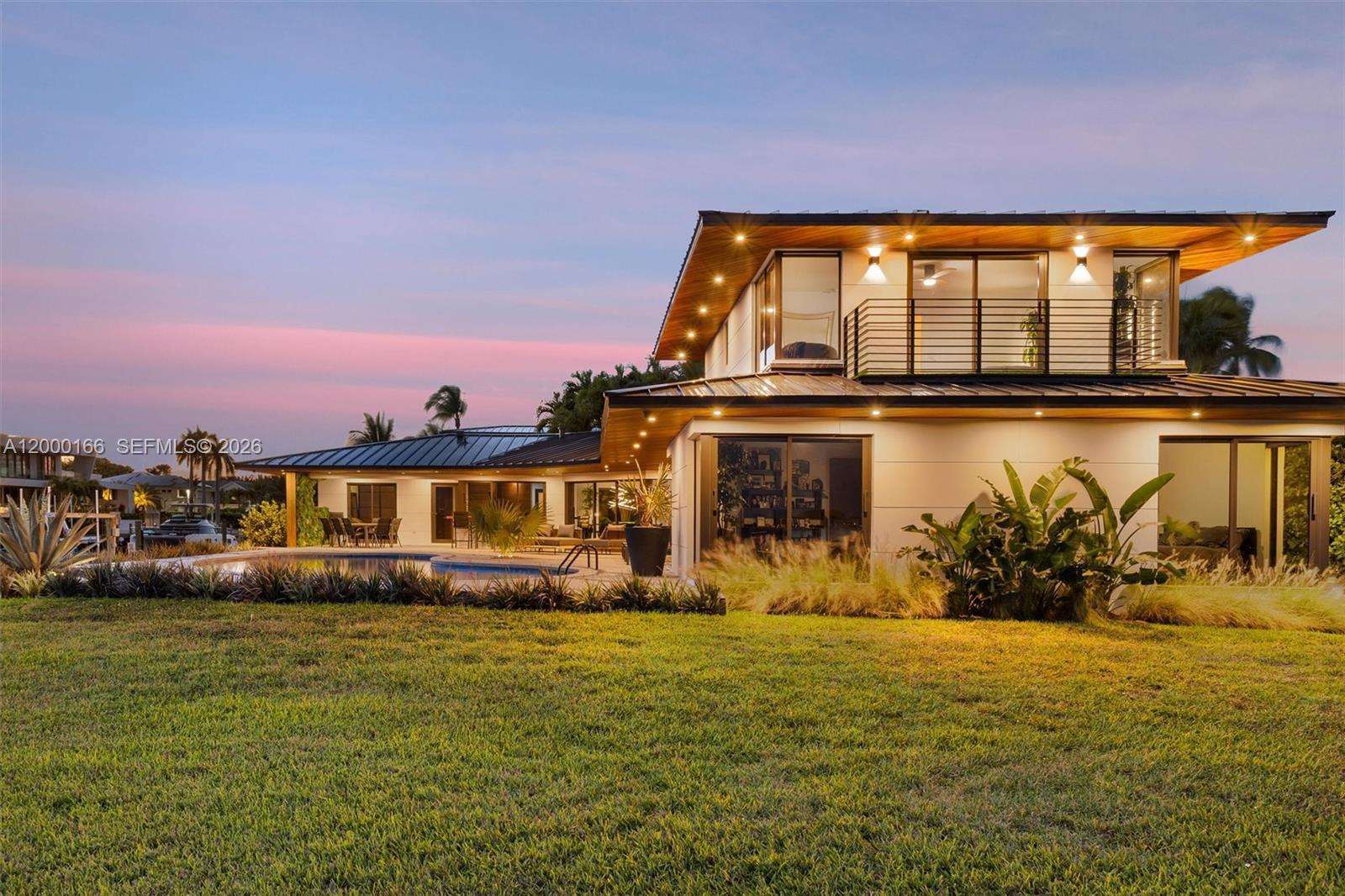 A modern two-story house with a pool and patio overlooks a grassy lawn at sunset — 1982 NE 119th Rd, North Miami FL 33181, NORTH MIAMI, FL