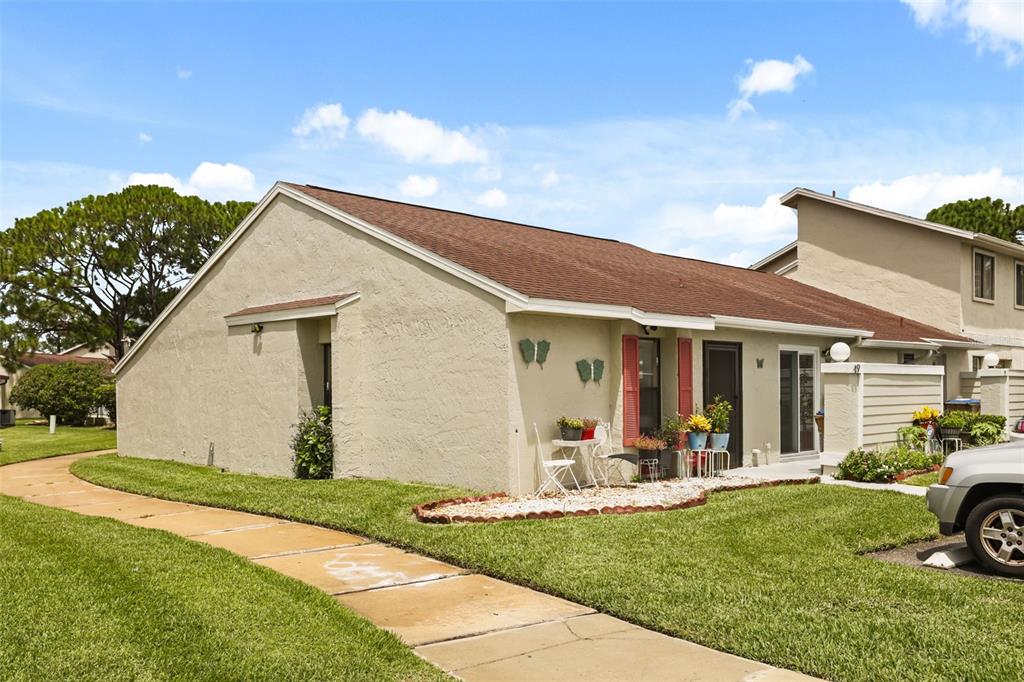 A single-story tan stucco townhouse with a brown shingled roof and a front walkway — 49 PINE ISLAND CIRCLE, KISSIMMEE, FL