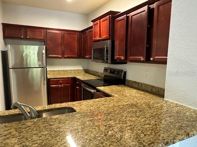 A kitchen features dark wood cabinets, granite countertops, and stainless steel appliances — 126 VISTA VERDI CIRCLE UNIT 204, LAKE MARY, FL