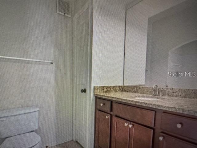 A bathroom features a dark wood vanity with a granite countertop and a toilet — 126 VISTA VERDI CIRCLE UNIT 204, LAKE MARY, FL