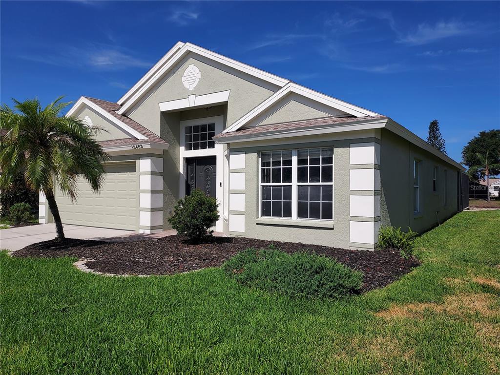 A single-story house with a light green stucco exterior, white trim, and a two-car garage — 12603 MIDPOINTE DRIVE, RIVERVIEW, FL