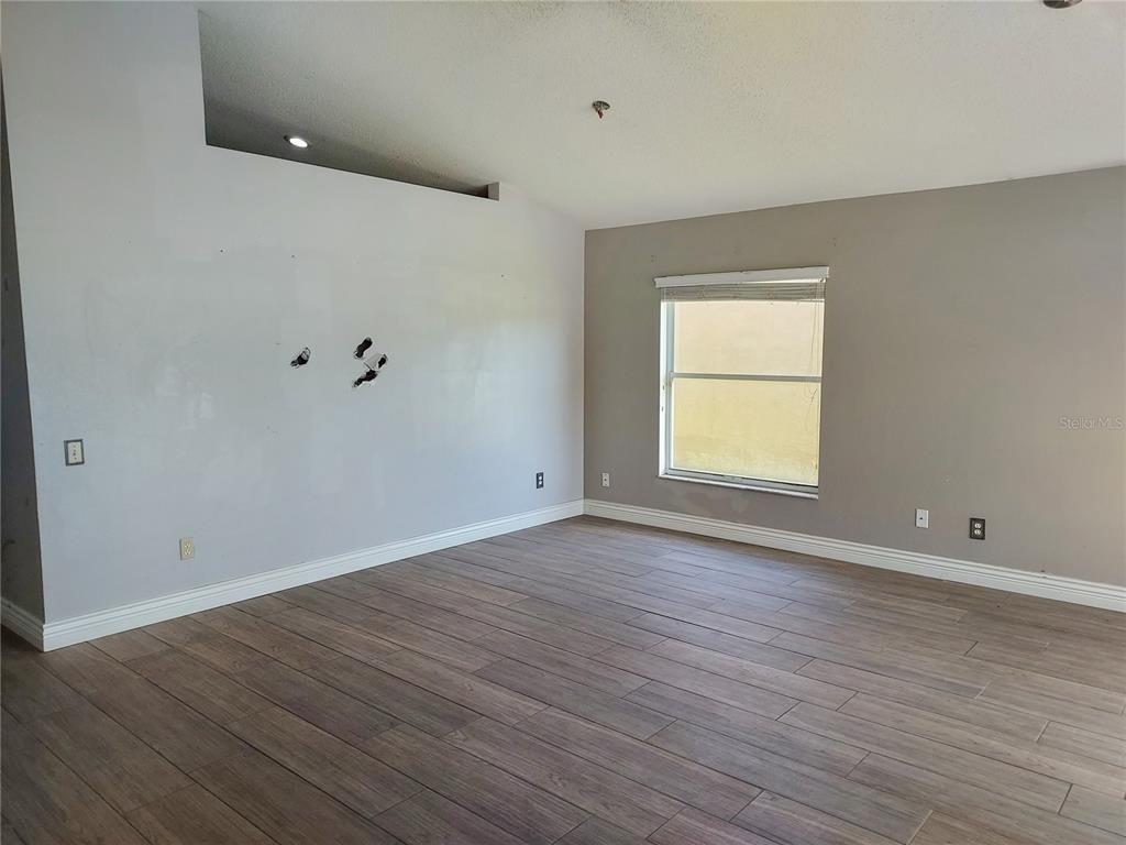 An empty room features light gray walls, wood-look tile flooring, and a single window — 12603 MIDPOINTE DRIVE, RIVERVIEW, FL