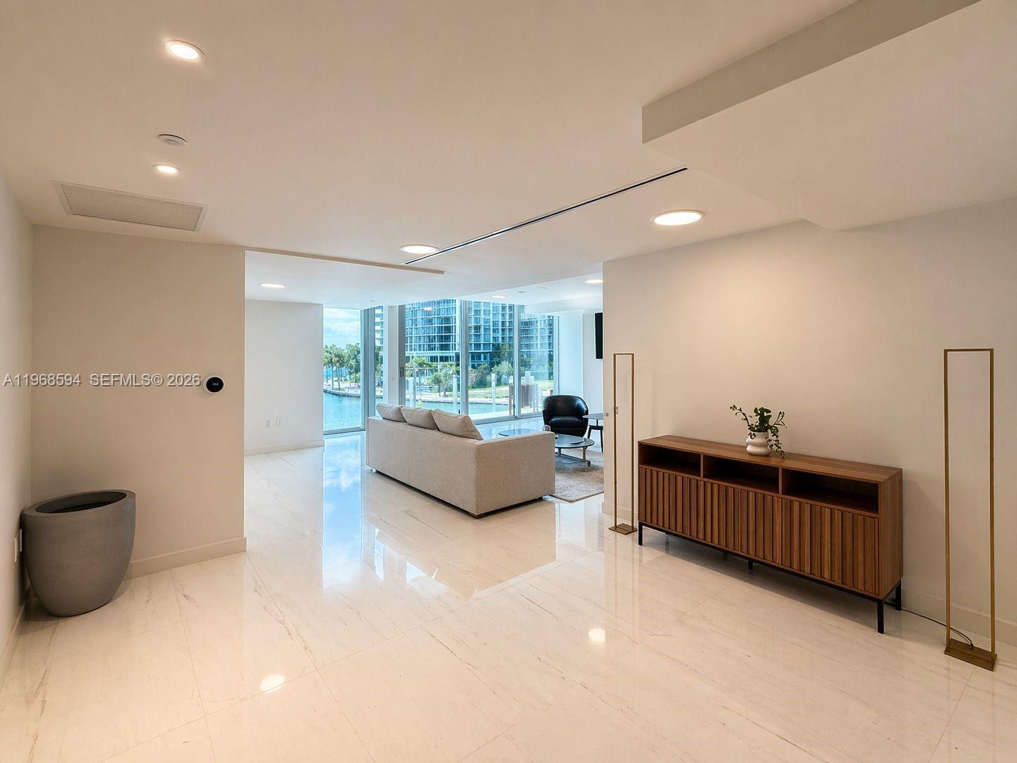 A bright living room features white tile floors, a wooden console, and floor-to-ceiling windows — 300 Biscayne Blvd Way # 303, Miami FL 33131, MIAMI, FL