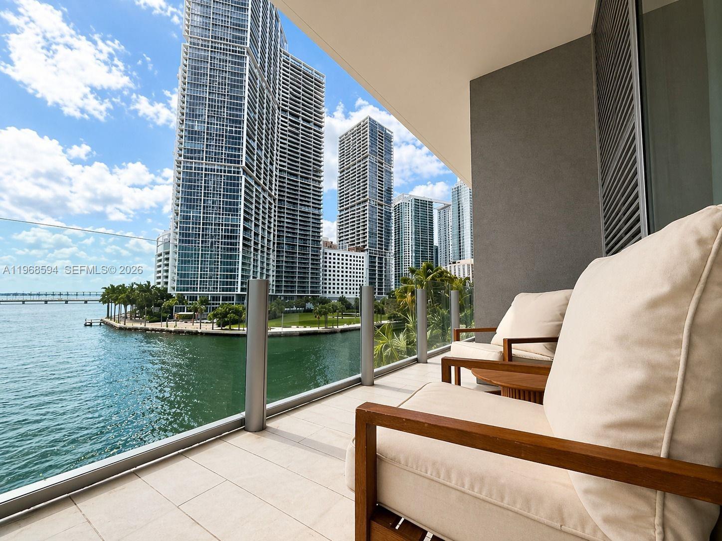 A balcony with two chairs overlooks a bay and several high-rise buildings — 300 Biscayne Blvd Way # 303, Miami FL 33131, MIAMI, FL