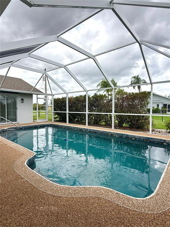 A screened-in swimming pool with a textured deck and surrounding palm trees — 167 MOCHA COURT, PUNTA GORDA, FL