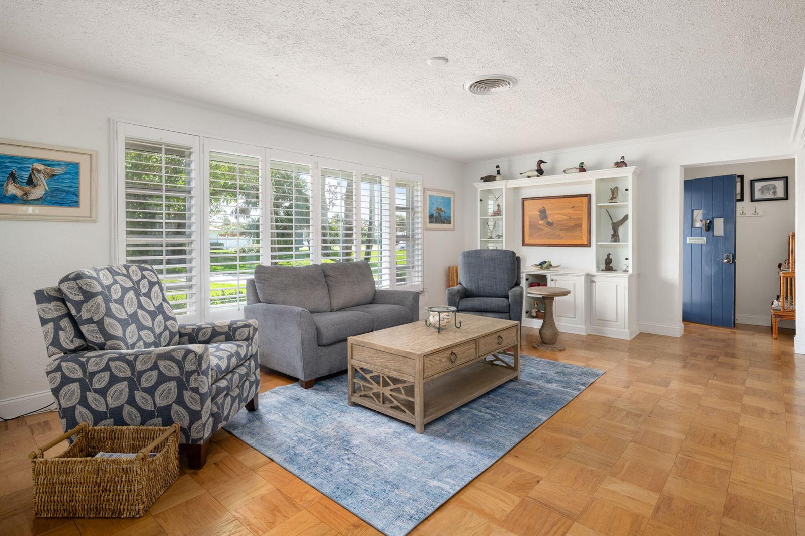 A living room with hardwood floors, a blue area rug, and white built-in shelving — 715 Conn Way, Vero Beach FL 32963, VERO BEACH, FL