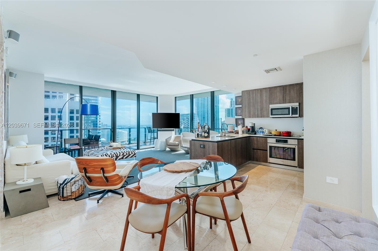 A modern open-concept living and dining area with floor-to-ceiling windows and city views — 68 SE 6th St # 2601, Miami FL 33131, MIAMI, FL