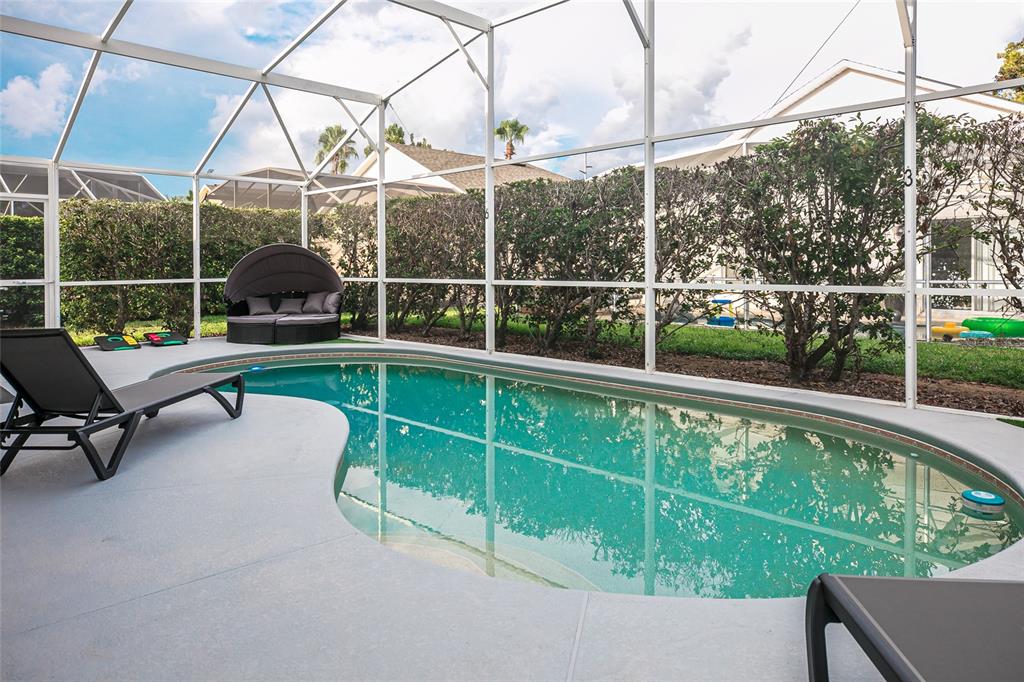 A swimming pool with a lounge chair sits inside a screened-in patio enclosure — 146 BAYSWATER LANE, DAVENPORT, FL