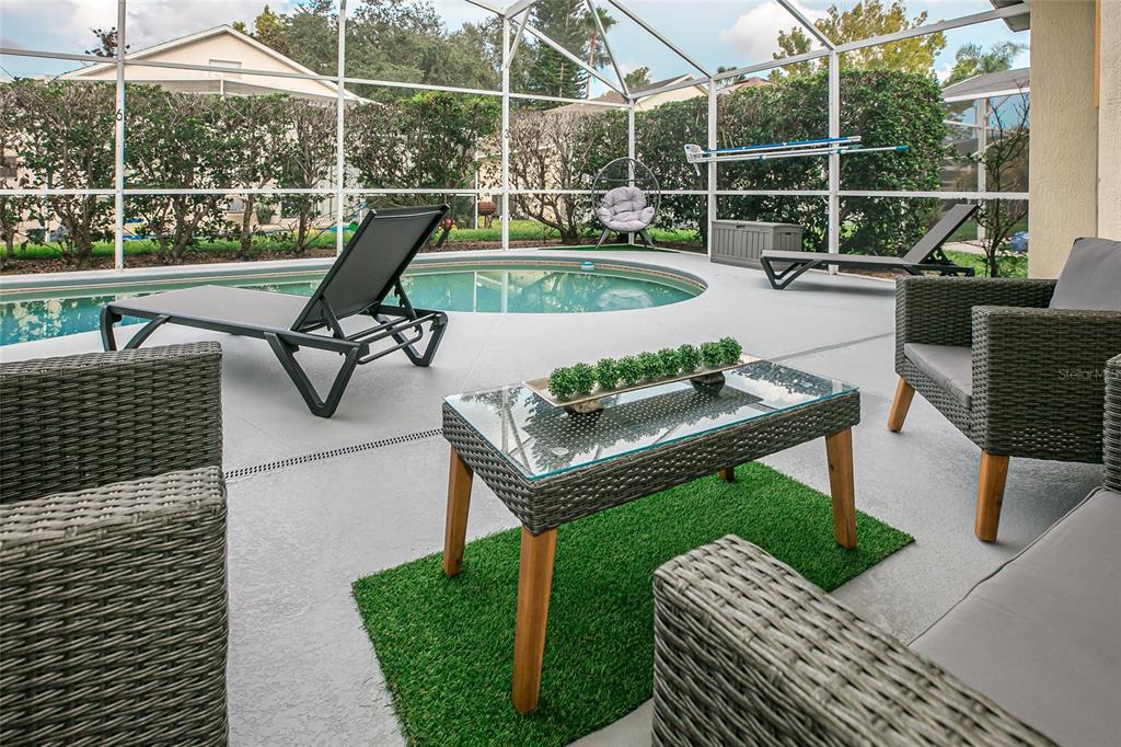 A screened-in patio features a small swimming pool, outdoor furniture, and a glass-topped coffee table — 146 BAYSWATER LANE, DAVENPORT, FL