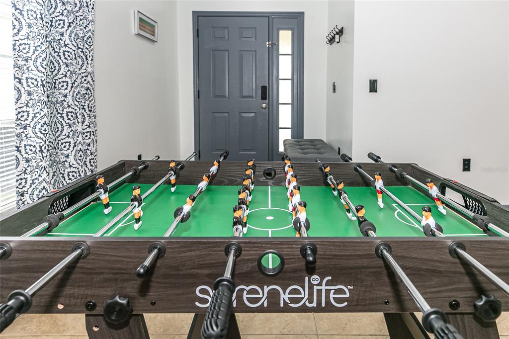 A foosball table sits in a room with a gray front door and tiled floors — 146 BAYSWATER LANE, DAVENPORT, FL