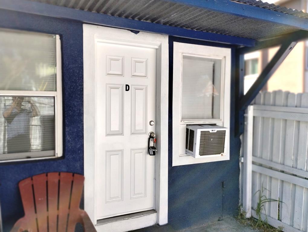 A white door labeled D with a window air conditioner unit on a blue exterior wall — 418 E AMELIA AVENUE UNIT D, TAMPA, FL