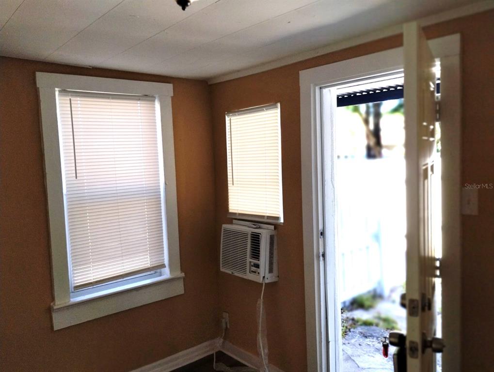 A room with tan walls, two windows with blinds, a window air conditioner, and an open door — 418 E AMELIA AVENUE UNIT D, TAMPA, FL