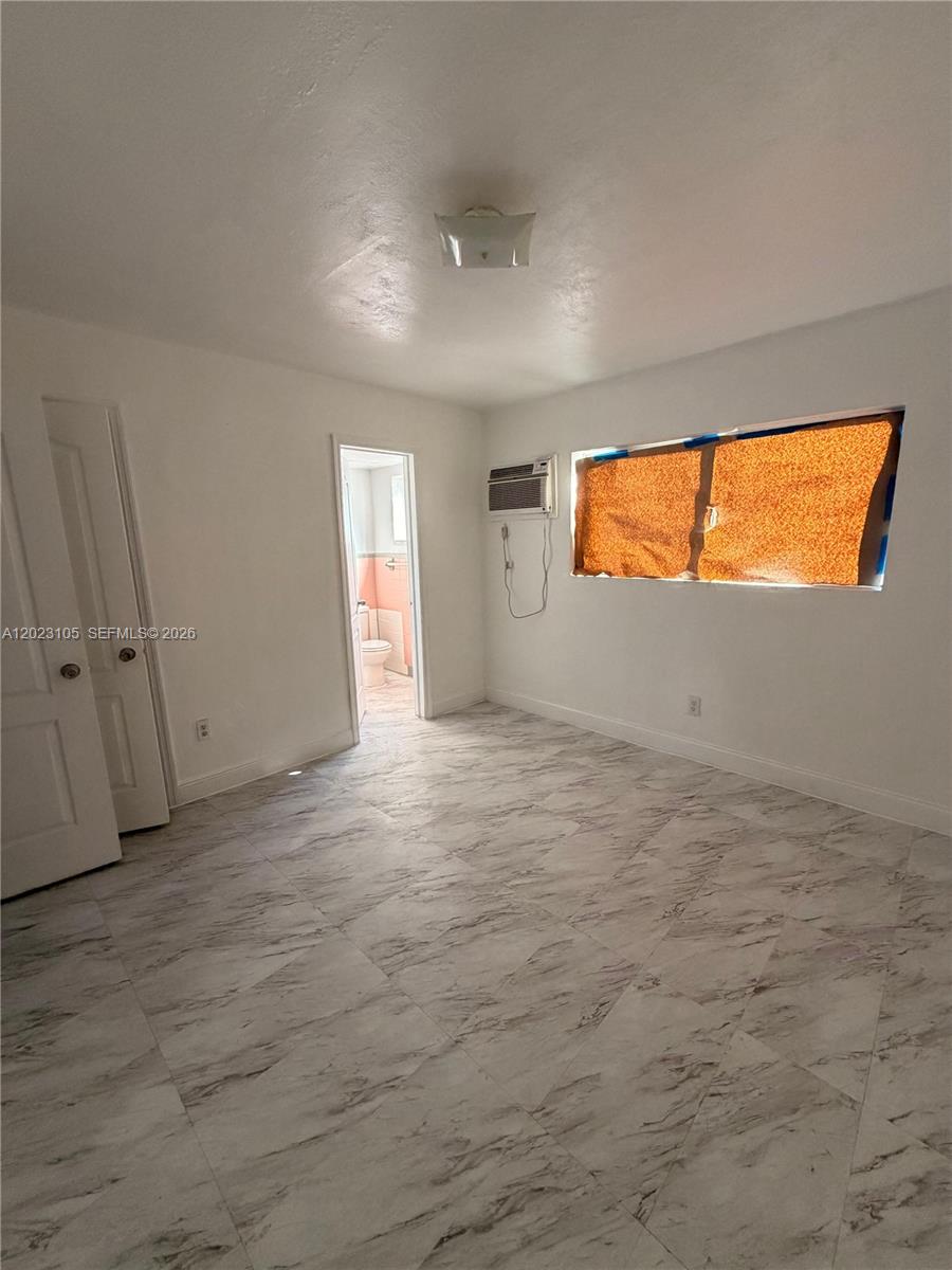 A room with white walls, marble-patterned tile flooring, a window, and an attached bathroom — 154 W 26th St # 2, Hialeah FL 33010, HIALEAH, FL