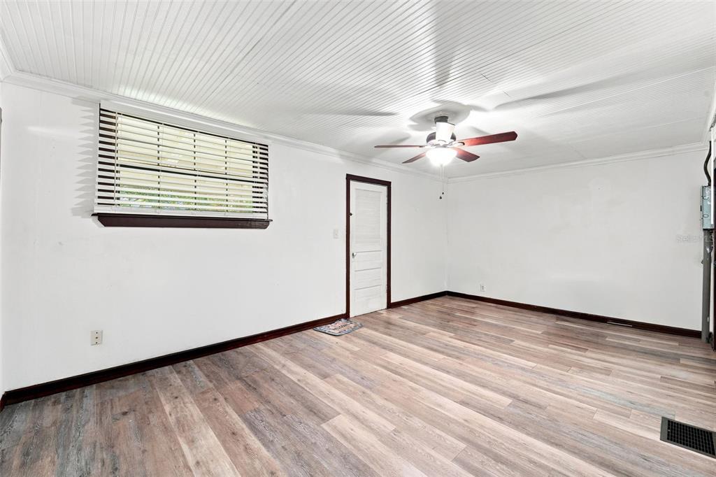 A room with white walls, a beadboard ceiling, a ceiling fan, and wood-look flooring — 316 S AMELIA AVENUE, DELAND, FL