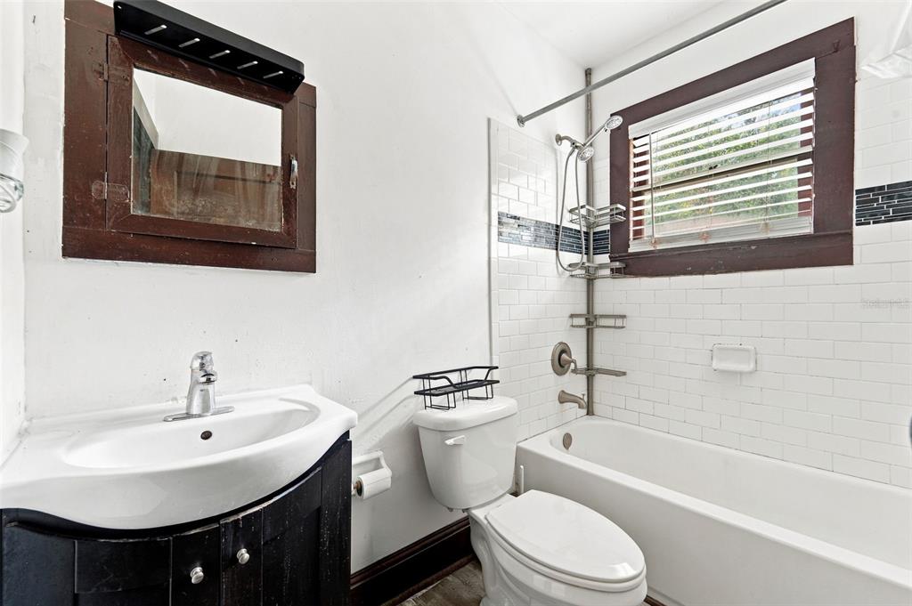 A bathroom features a white pedestal sink, a toilet, and a bathtub with subway tile — 316 S AMELIA AVENUE, DELAND, FL