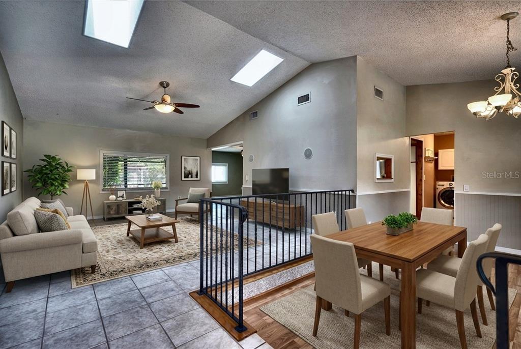 A living and dining area with vaulted ceilings, skylights, tile flooring, and a metal railing — 2724 ABBEY AVENUE, ORLANDO, FL