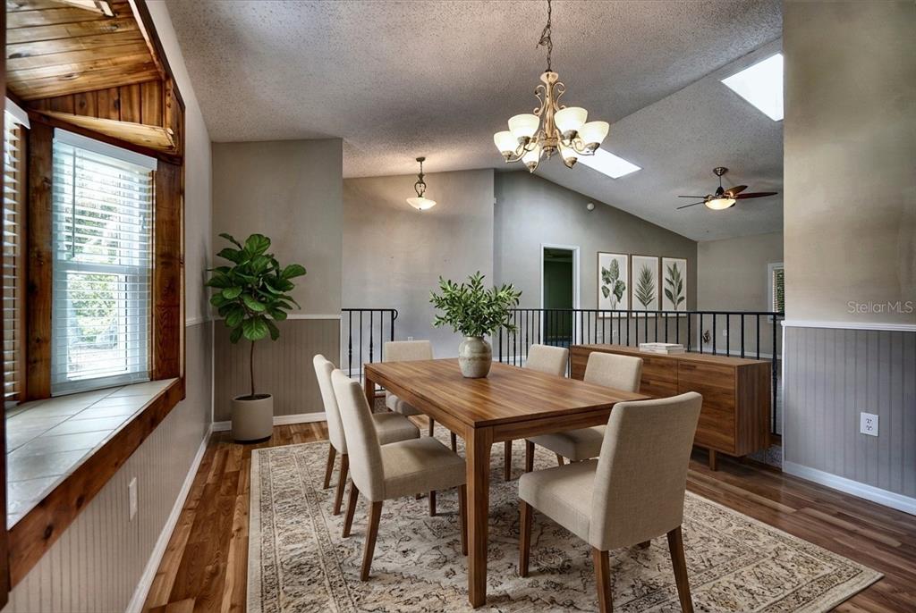 A dining room with a wooden table, beige chairs, a chandelier, and a vaulted ceiling — 2724 ABBEY AVENUE, ORLANDO, FL