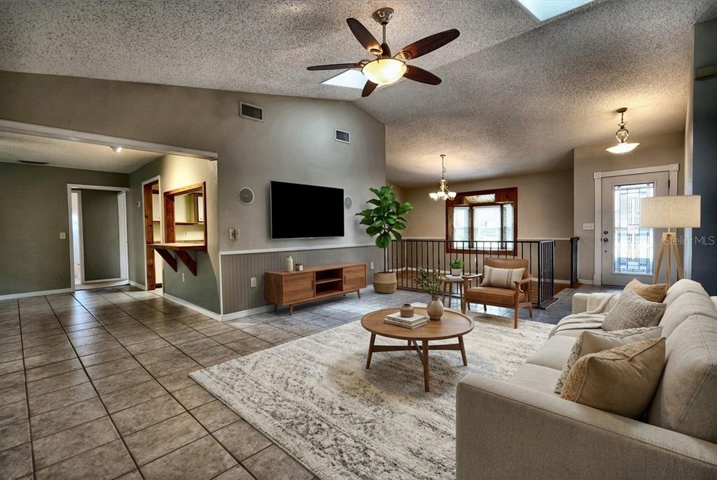 A living room features tile floors, a vaulted ceiling with a fan, and a television — 2724 ABBEY AVENUE, ORLANDO, FL