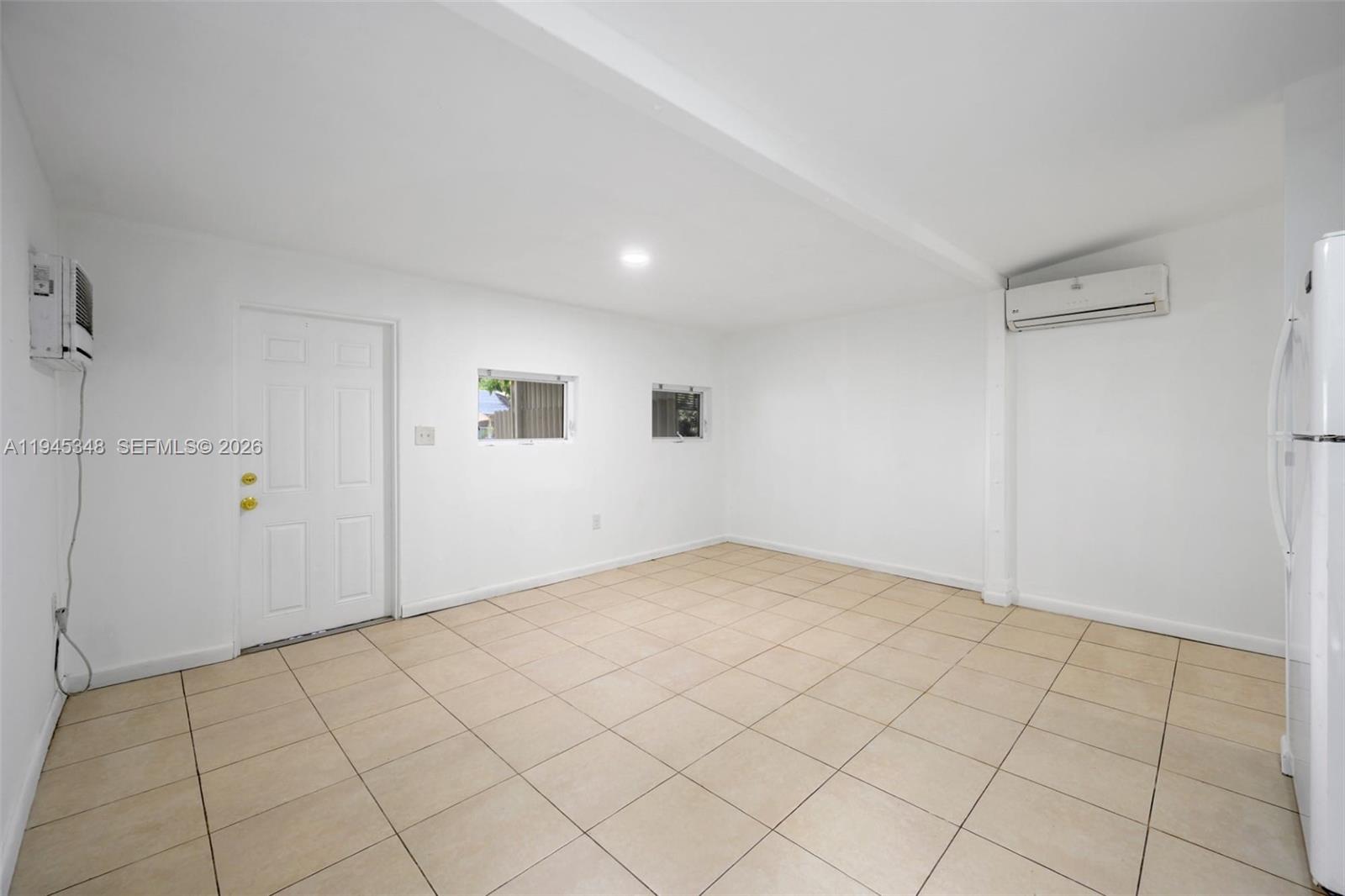 A room with white walls, tiled floors, a door, two small windows, and air conditioning units — 348 NE 58th St, Miami FL 33137, MIAMI, FL