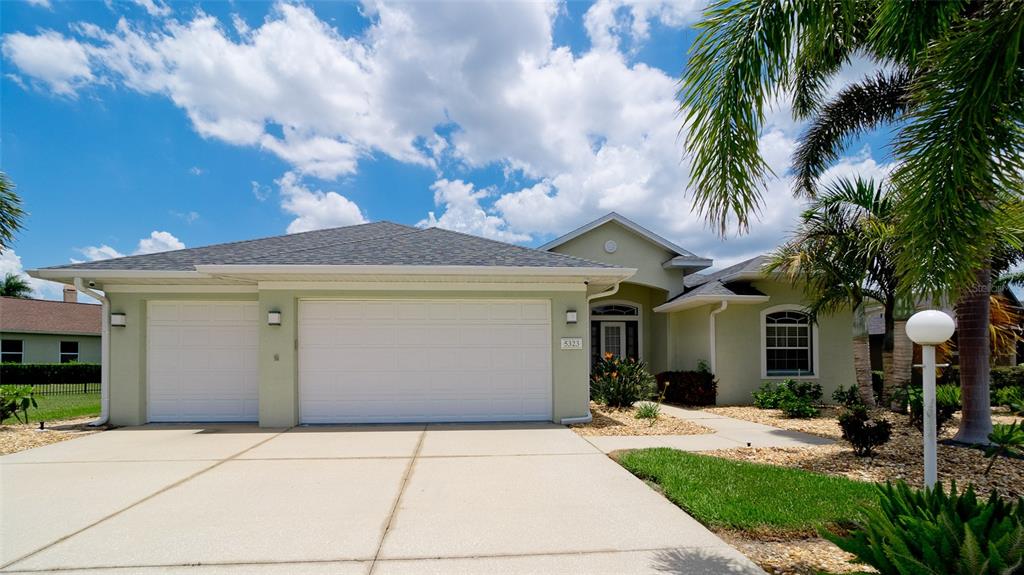 A single-story house with a two-car garage and a paved driveway under a blue sky — 5323 90TH AVENUE CIRCLE E, PARRISH, FL