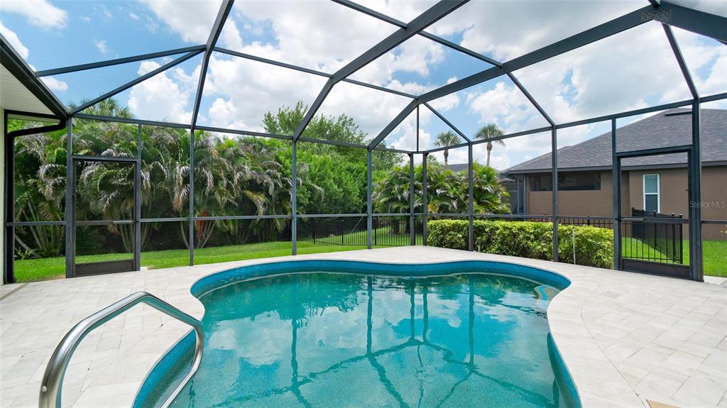A screened-in patio features a kidney-shaped swimming pool and light-colored pavers — 5323 90TH AVENUE CIRCLE E, PARRISH, FL
