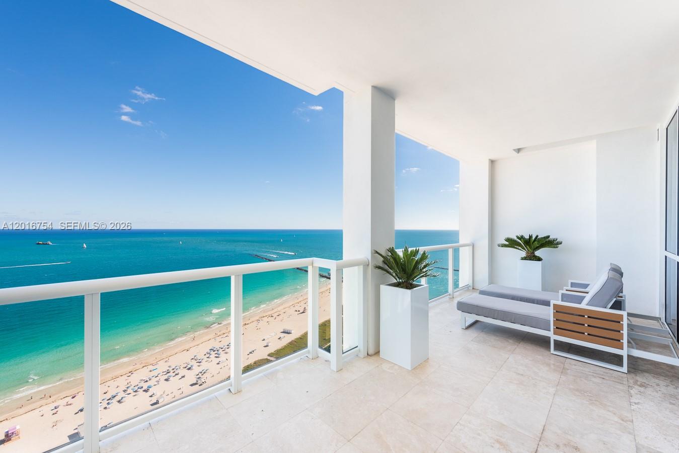 A balcony with tile flooring overlooks the ocean and beach, featuring two lounge chairs — 50 S Pointe Dr # 3302, Miami Beach FL 33139, MIAMI BEACH, FL