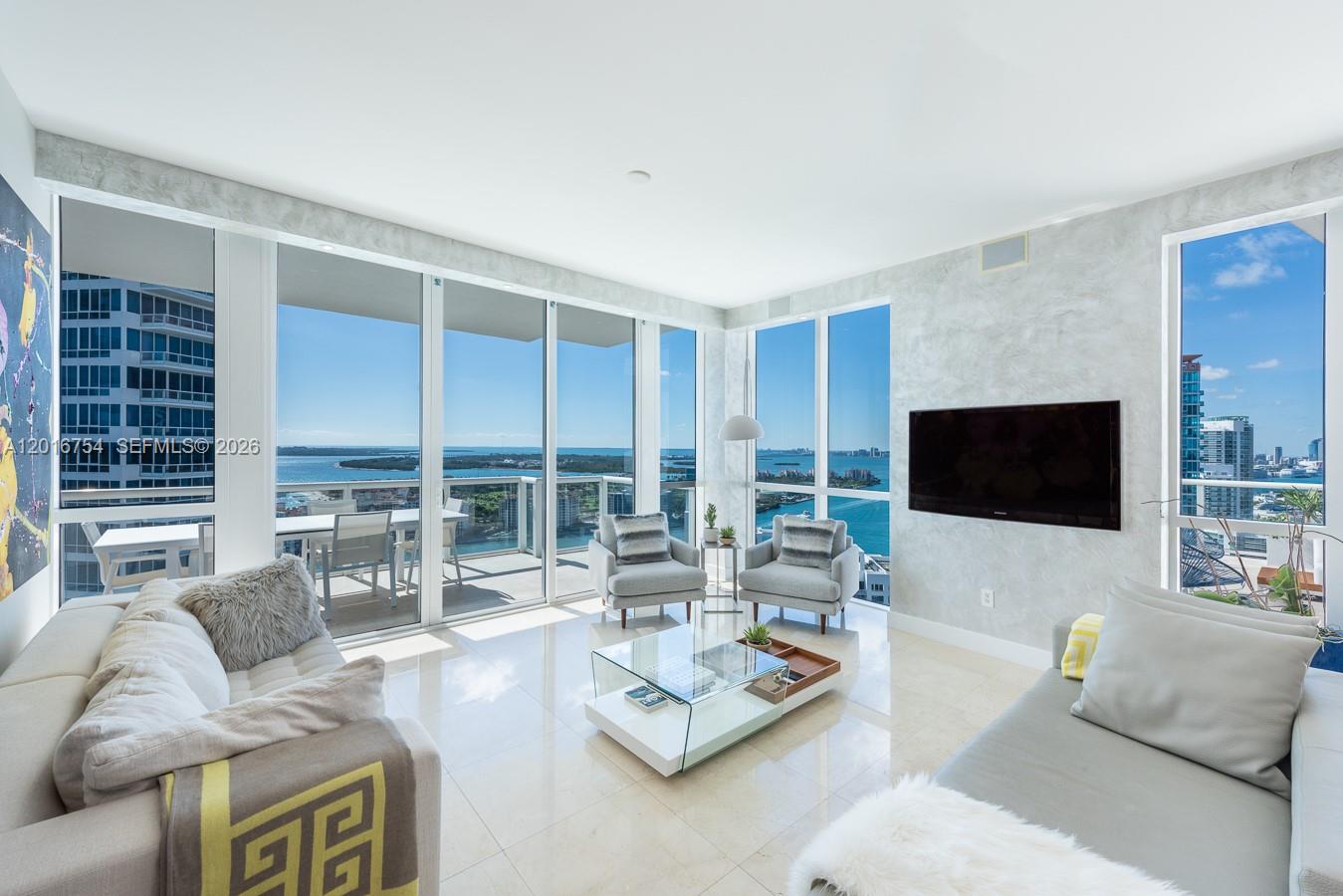 A modern living room features floor-to-ceiling windows with panoramic water views and tiled floors — 50 S Pointe Dr # 3302, Miami Beach FL 33139, MIAMI BEACH, FL