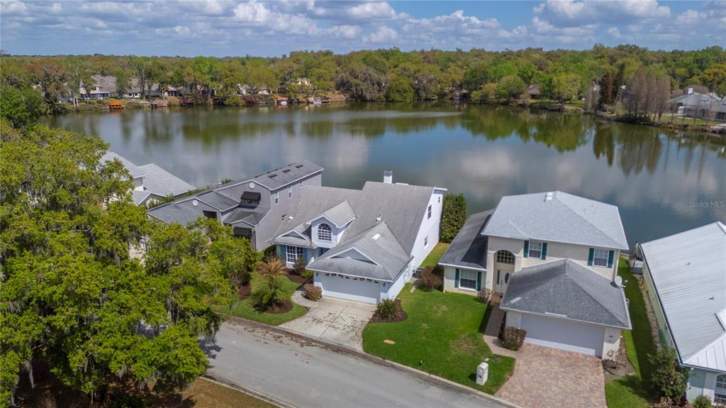 An aerial view shows two suburban houses situated along the edge of a lake — 725 PENINSULAR DRIVE, LAKELAND, FL