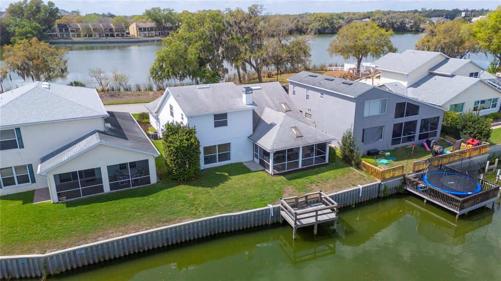 An aerial view shows three waterfront houses with backyard lawns, screened porches, and wooden docks — 725 PENINSULAR DRIVE, LAKELAND, FL