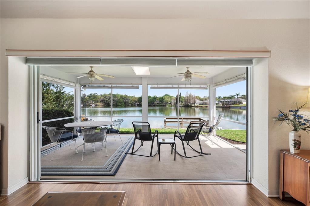A view from inside looking out through sliding glass doors to a screened-in lakeside patio — 725 PENINSULAR DRIVE, LAKELAND, FL