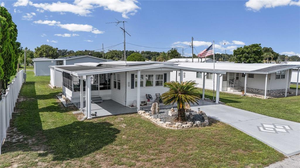 A white mobile home features a screened porch, a palm tree, and a paved driveway — 37250 BEVERLY AVENUE, ZEPHYRHILLS, FL