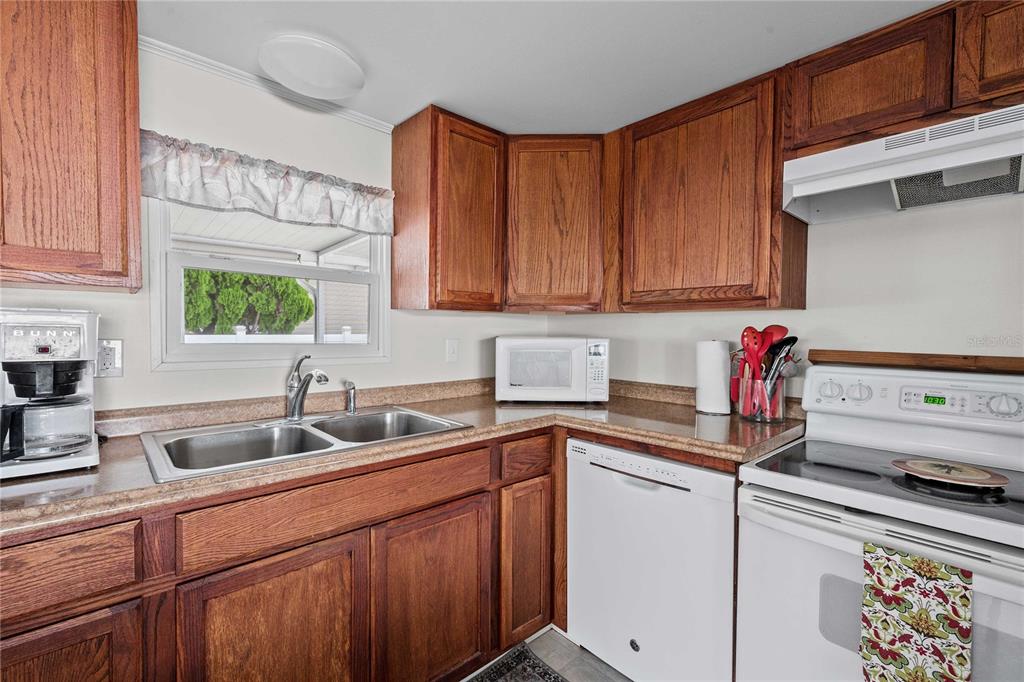 A kitchen features wood cabinets, laminate countertops, a double sink, and white appliances — 37250 BEVERLY AVENUE, ZEPHYRHILLS, FL