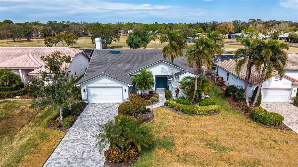 An aerial view of a single-story suburban house with a tiled roof and paved driveway — 5515 DOWNHAM MEADOWS, SARASOTA, FL