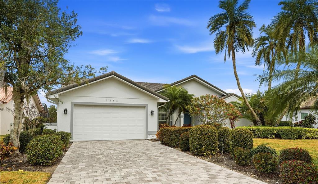 A single-story house with a white stucco exterior, a two-car garage, and a paved driveway — 5515 DOWNHAM MEADOWS, SARASOTA, FL