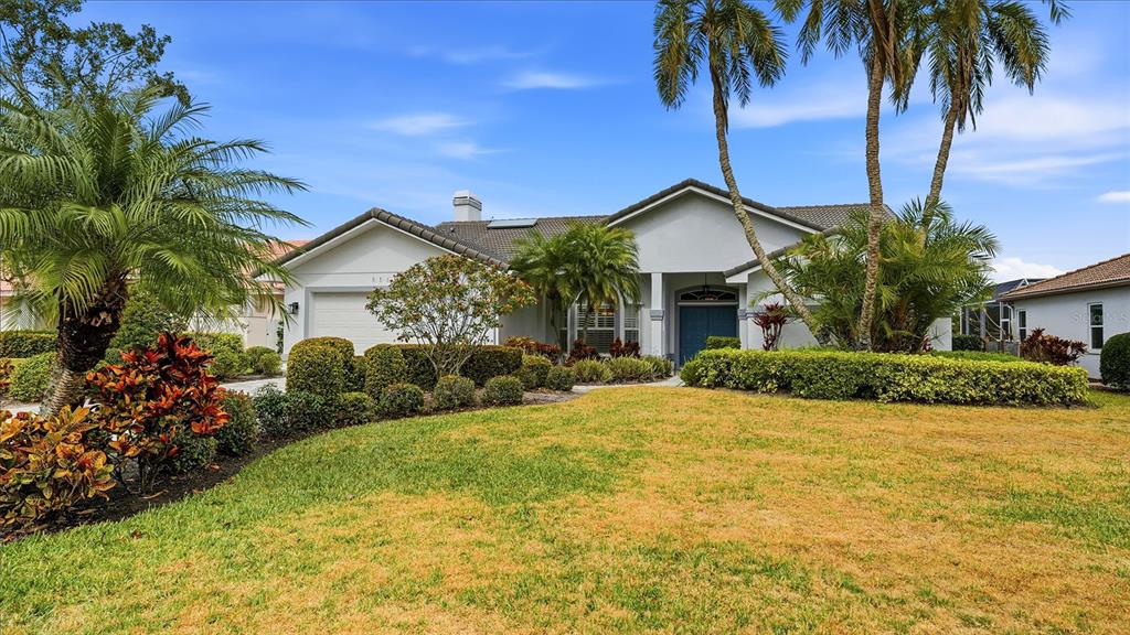 A single-story house with a light-colored exterior, a tiled roof, and a landscaped front yard — 5515 DOWNHAM MEADOWS, SARASOTA, FL