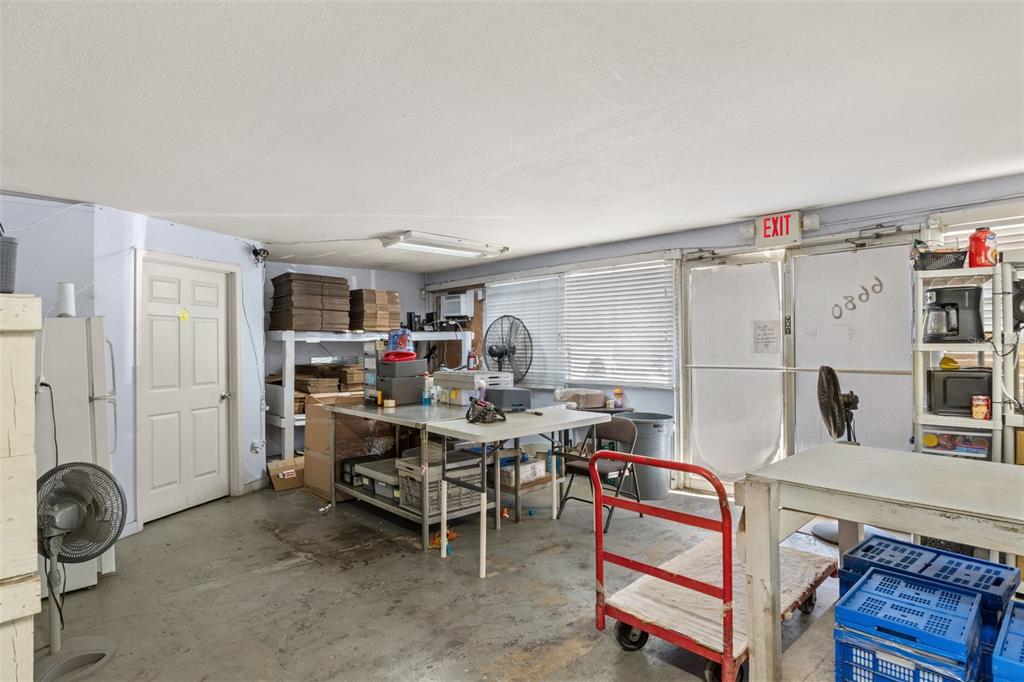 A utility or storage room features concrete floors, metal work tables, shelving, and an exit door — 6680 W GULF TO LAKE HIGHWAY, CRYSTAL RIVER, FL