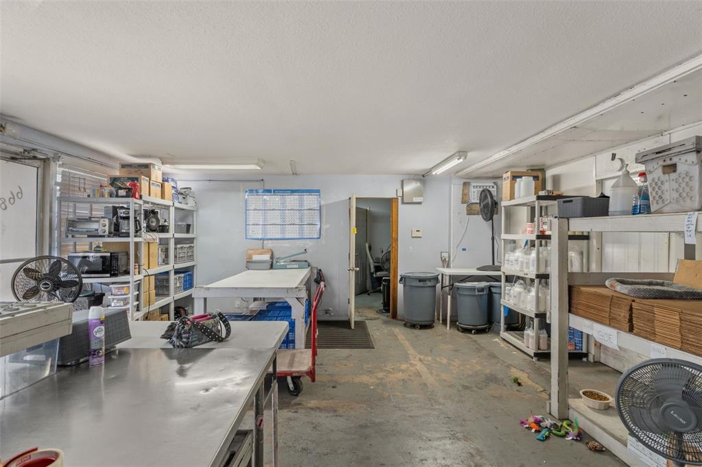 A cluttered utility or storage room features metal shelving, work tables, and concrete flooring — 6680 W GULF TO LAKE HIGHWAY, CRYSTAL RIVER, FL